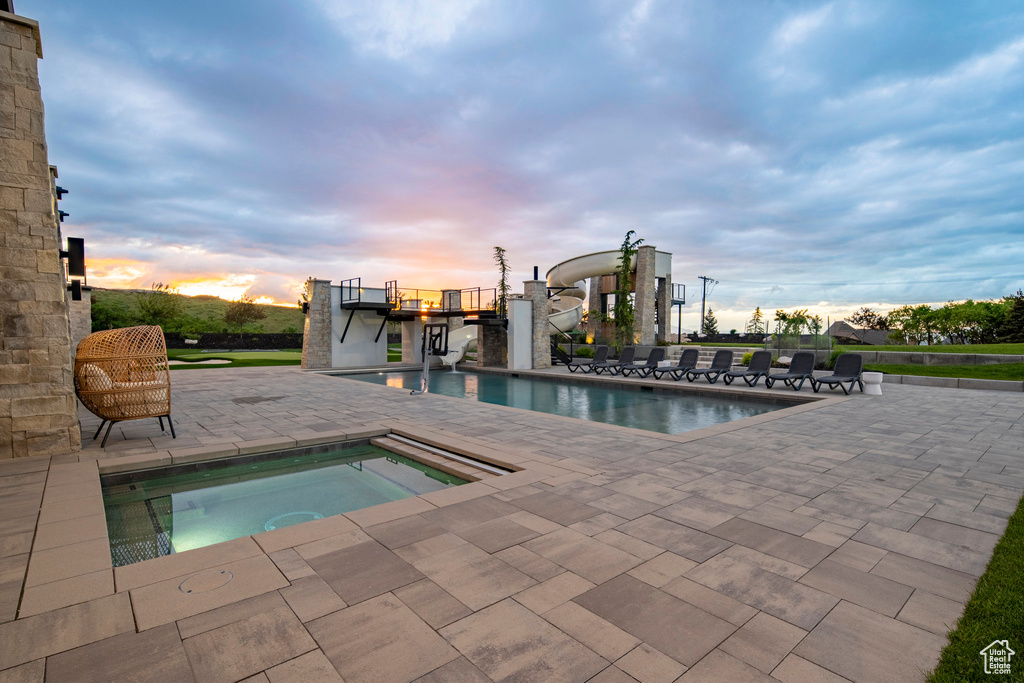 Pool at dusk featuring a patio area, an in-ground hot tub, and an outdoor pool