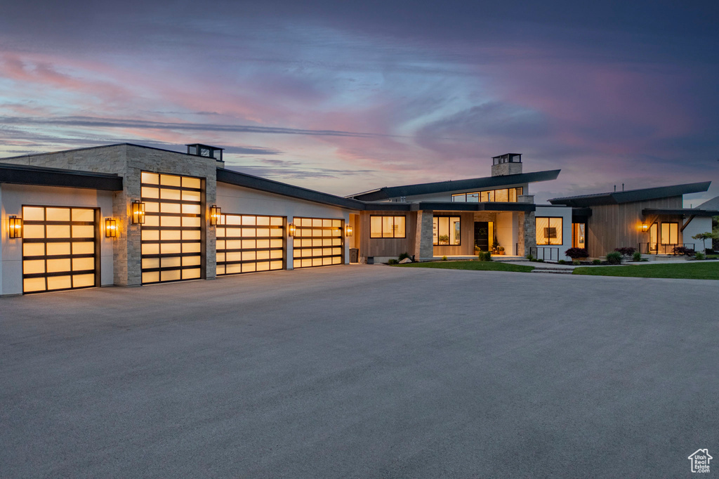 Contemporary home with an attached garage, asphalt driveway, and stone siding