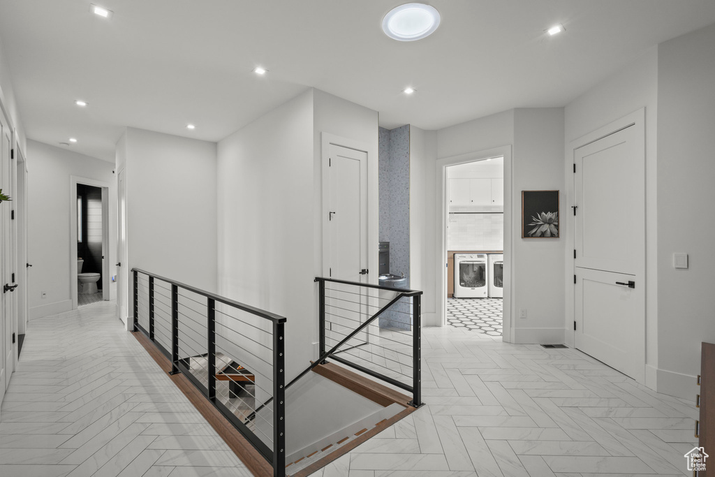 Hall featuring an upstairs landing, baseboards, washing machine and clothes dryer, and recessed lighting