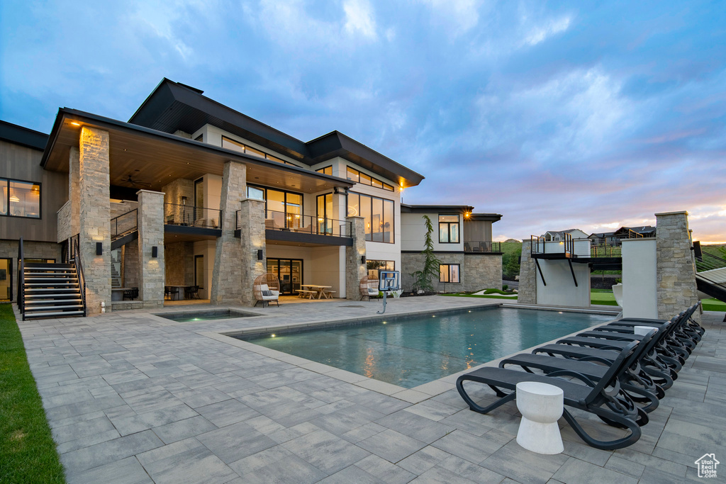 Pool at dusk with a patio, an outdoor pool, and stairway