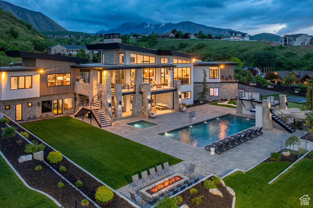 Rear view of property featuring an in-ground hot tub, a balcony, area for grilling, and a mountain view
