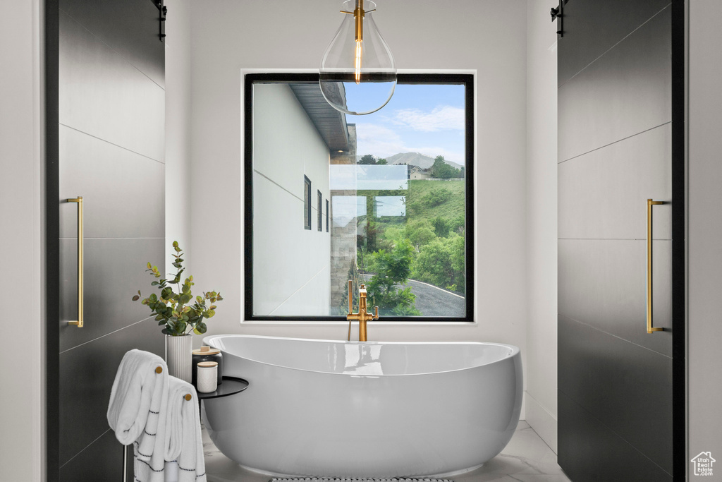 Full bath featuring a freestanding bath and marble finish floors