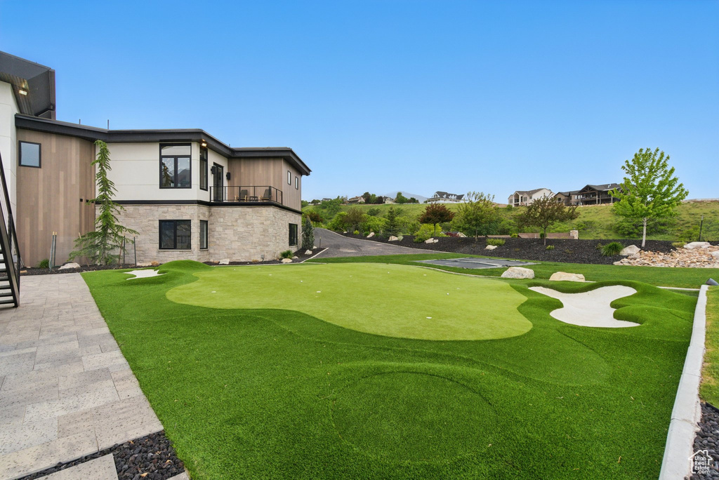 View of yard with an area to practice putting and a balcony