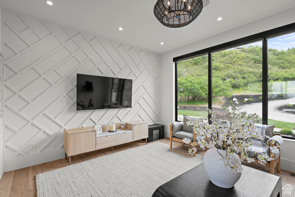 Living area with wood finished floors, a decorative wall, an accent wall, a chandelier, and recessed lighting