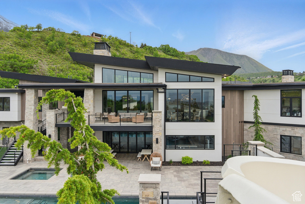 Back of property featuring a chimney, a patio area, a mountain view, an outdoor pool, and an outdoor living space