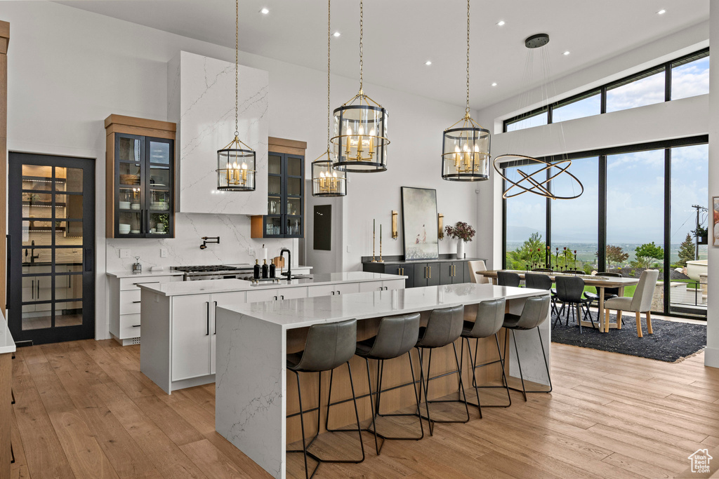 Kitchen with a spacious island, a chandelier, a high ceiling, light wood-type flooring, and pendant lighting
