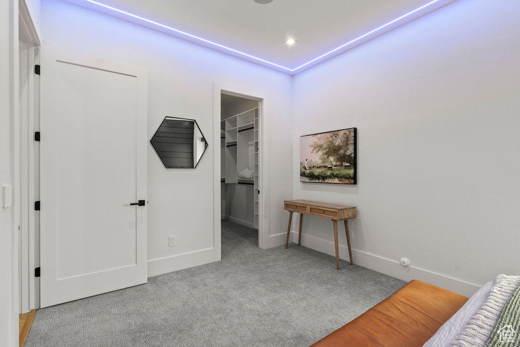 Carpeted bedroom with a walk in closet, baseboards, and a closet