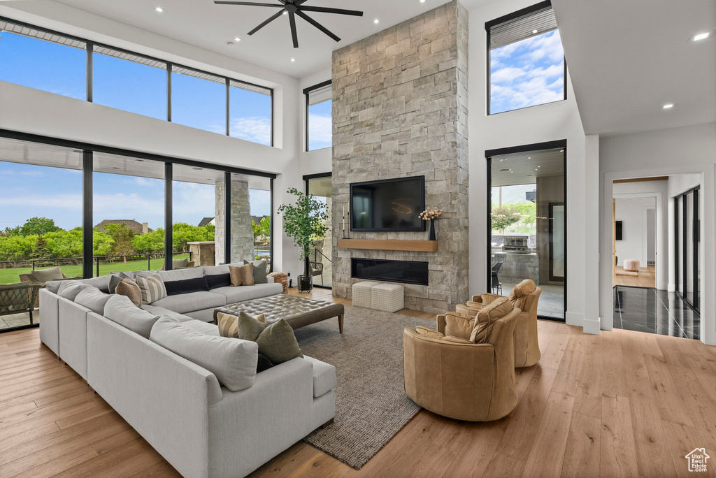 Living area featuring a towering ceiling, ceiling fan, plenty of natural light, a fireplace, and hardwood / wood-style floors