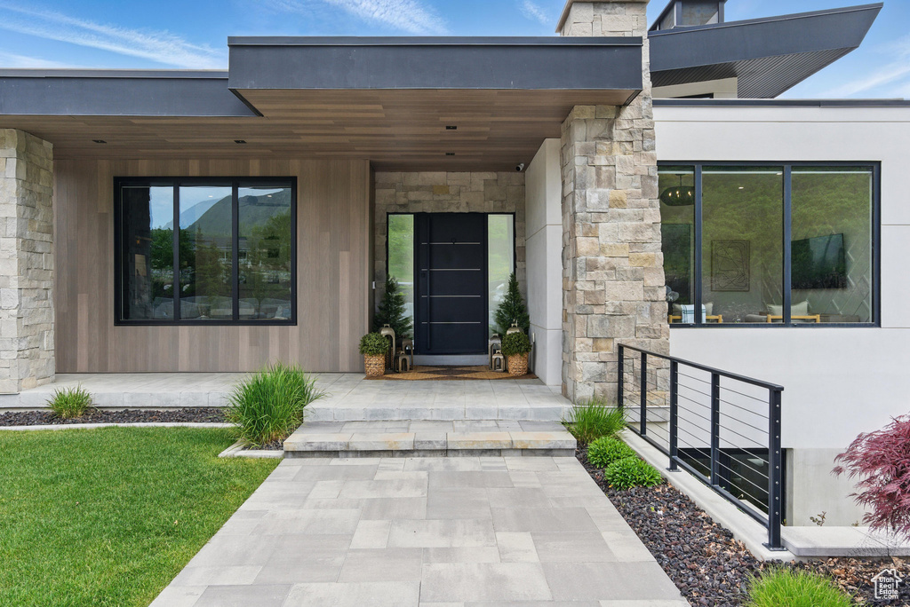 Property entrance with stone siding and a yard