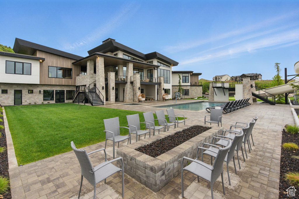 View of patio featuring stairs, a balcony, and an outdoor pool