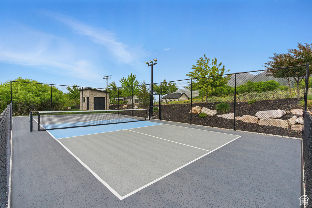 View of tennis court with fence and community basketball court