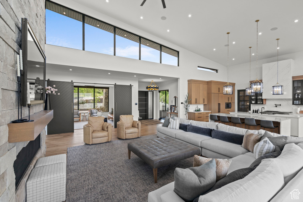 Living room featuring a high ceiling, light wood finished floors, recessed lighting, a chandelier, and ceiling fan
