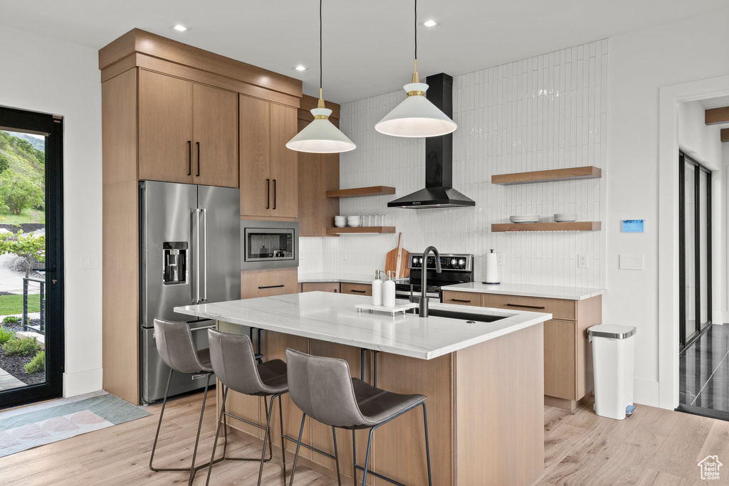 Kitchen with appliances with stainless steel finishes, open shelves, tasteful backsplash, light wood-type flooring, and light stone countertops