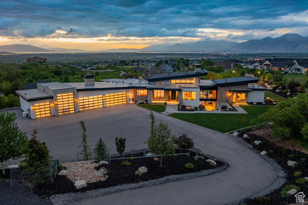 Contemporary house with a mountain view, curved driveway, a front lawn, and an attached garage