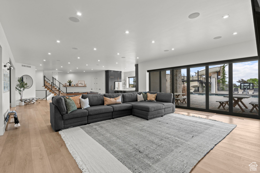 Living area featuring recessed lighting, healthy amount of natural light, stairs, and light wood-type flooring