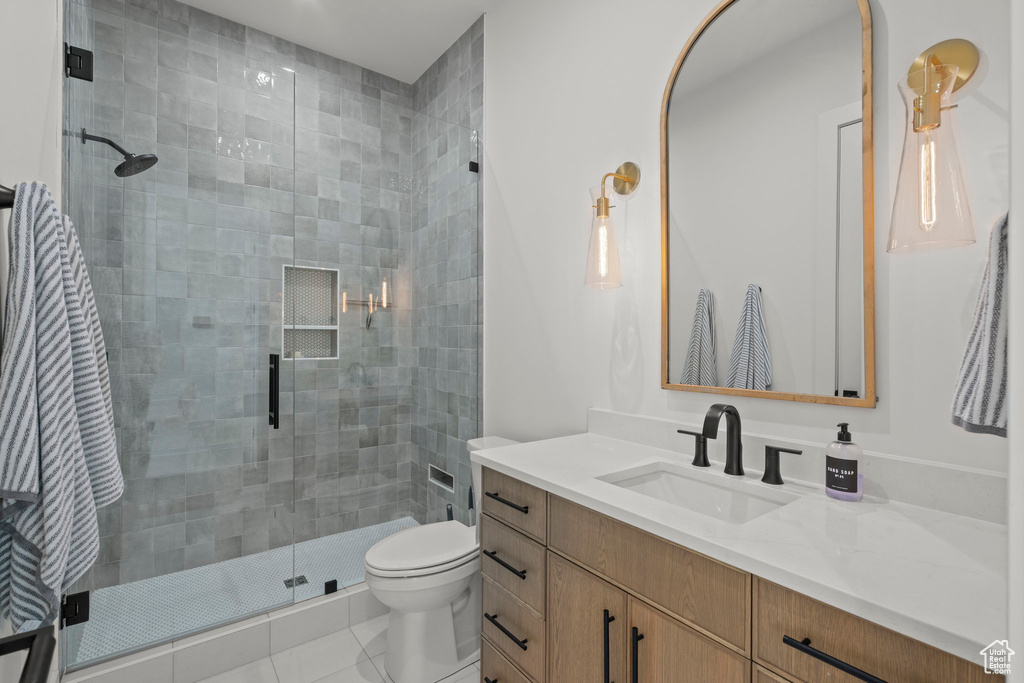 Full bathroom featuring a stall shower, toilet, vanity, and tile patterned floors