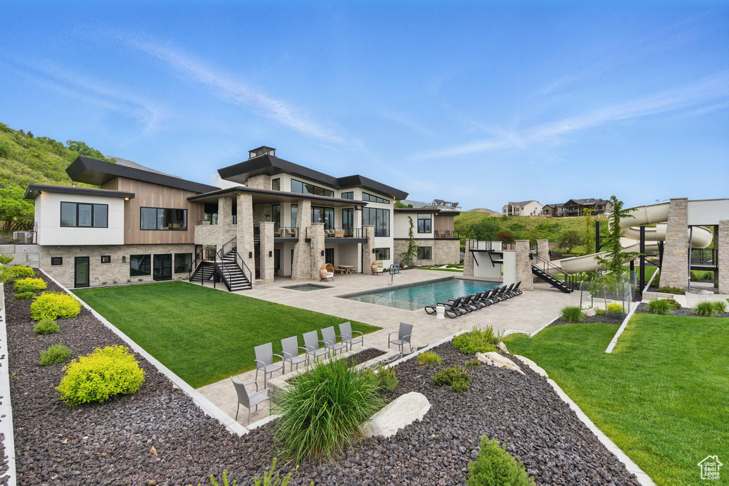 Rear view of house featuring stairway, a balcony, a patio, an outdoor pool, and a yard
