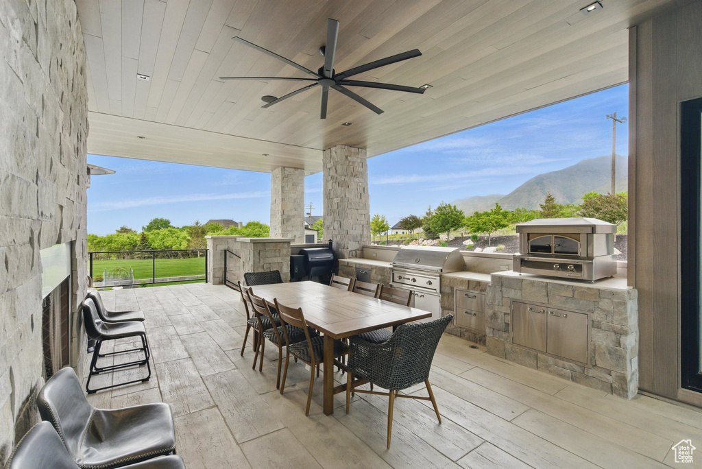 View of patio / terrace with exterior kitchen, grilling area, outdoor dining area, a mountain view, and ceiling fan