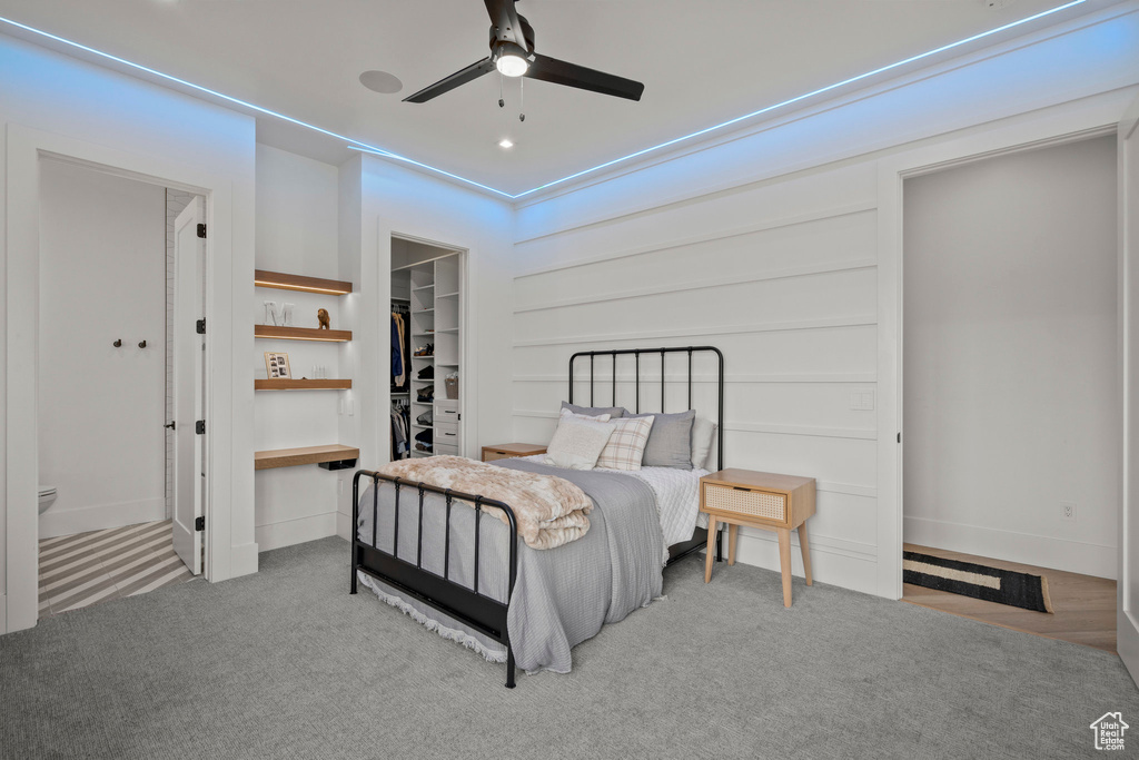 Carpeted bedroom featuring a walk in closet, a closet, and ceiling fan