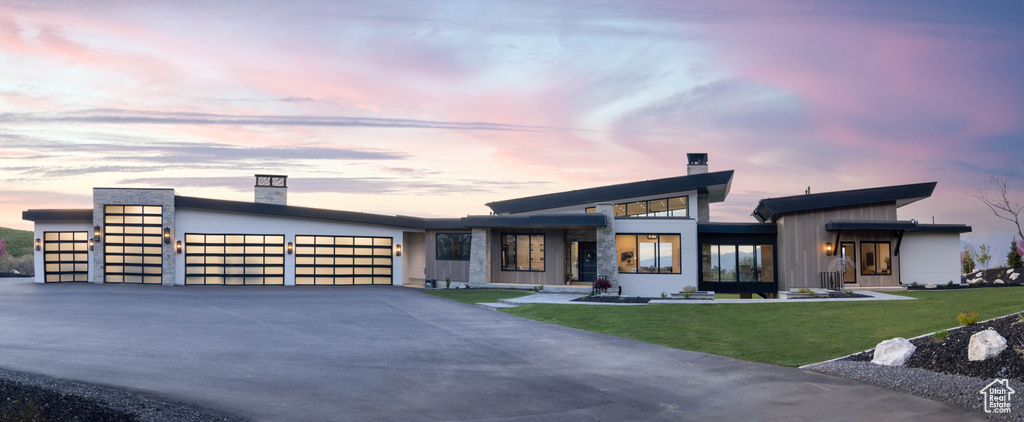 Modern home with a garage, a chimney, concrete driveway, and a front yard