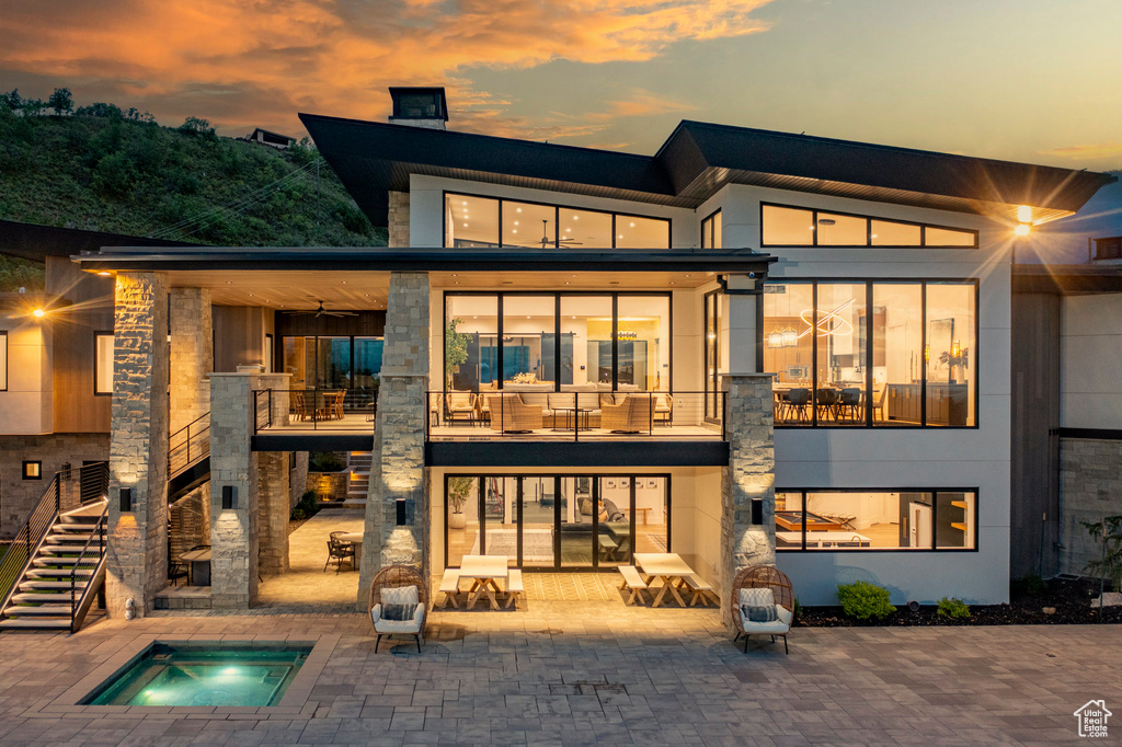 Rear view of house featuring an in-ground hot tub, a patio area, stairway, and a chimney