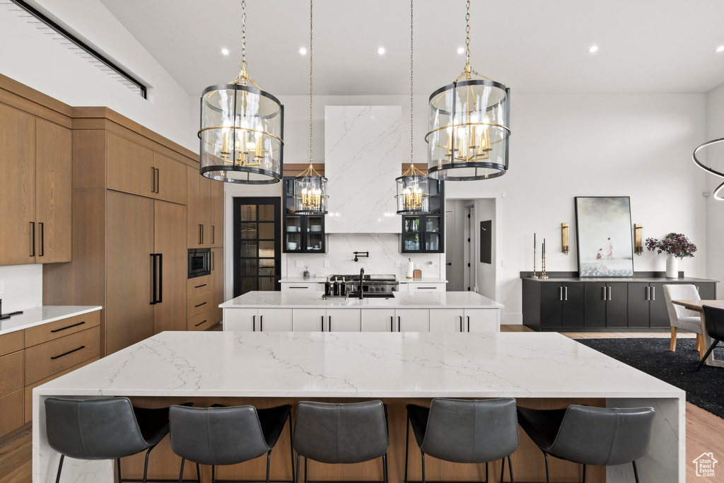 Kitchen with a spacious island, a chandelier, brown cabinets, a high ceiling, and recessed lighting