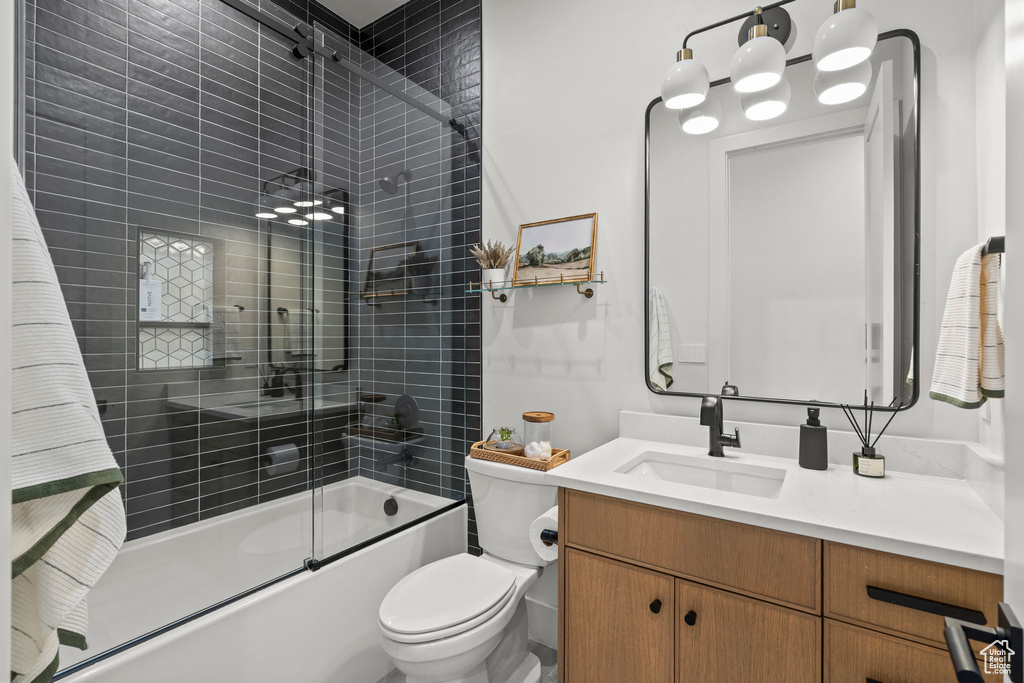 Bathroom featuring vanity, shower / bath combination with glass door, and toilet