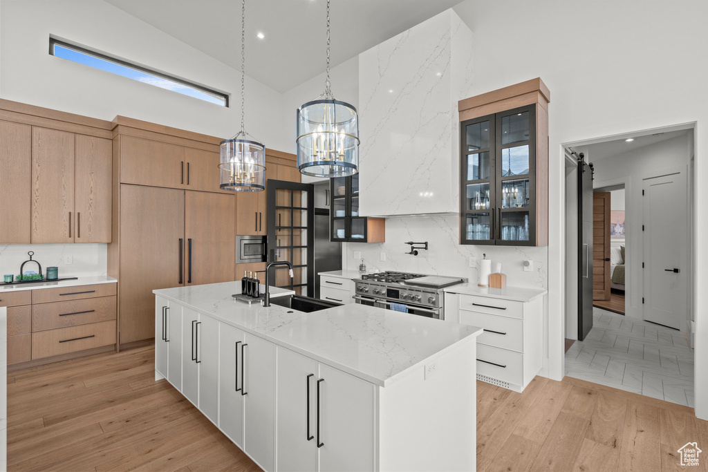 Kitchen with high vaulted ceiling, a sink, a chandelier, stainless steel appliances, and glass insert cabinets