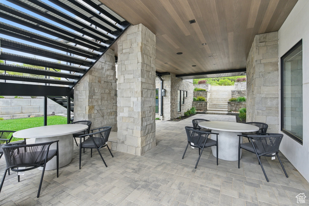 View of patio with outdoor dining area, stairway, a pergola, and fence