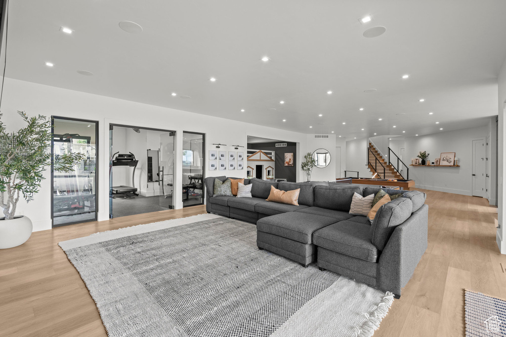 Living room with light wood-style floors, recessed lighting, and stairway