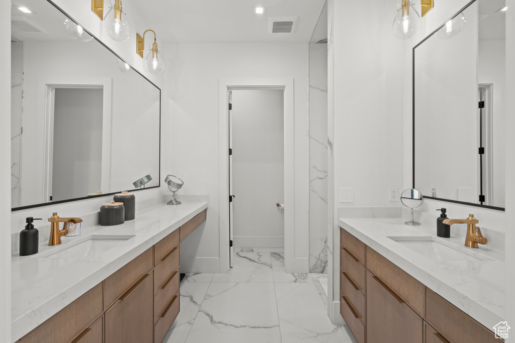Full bathroom featuring marble finish floors, two vanities, baseboards, and recessed lighting