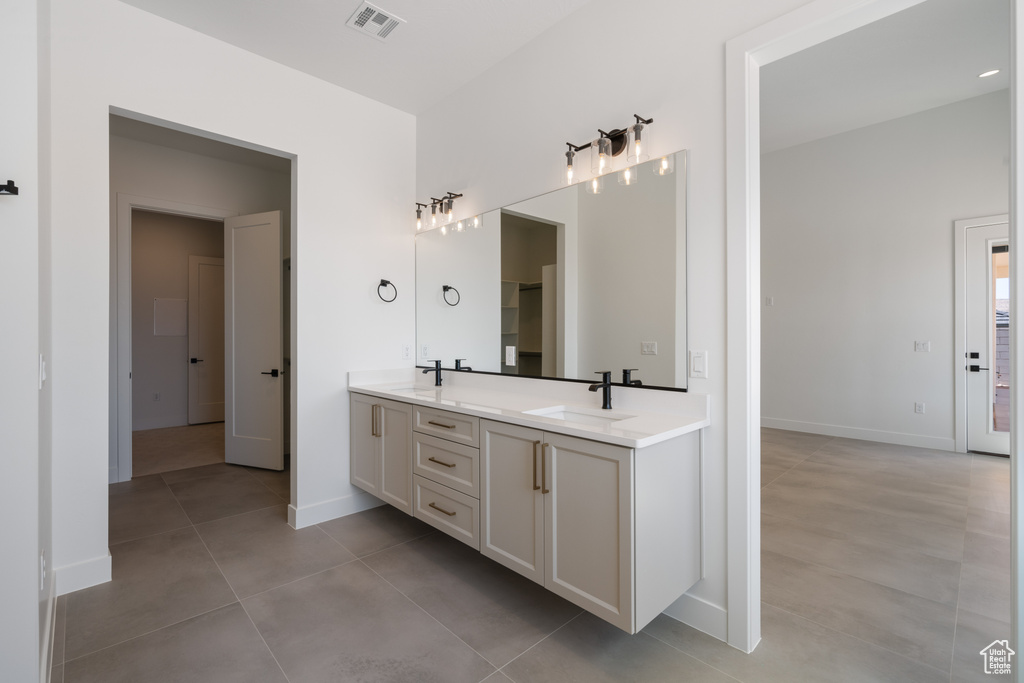 Full bath featuring double vanity, tile patterned floors, and baseboards