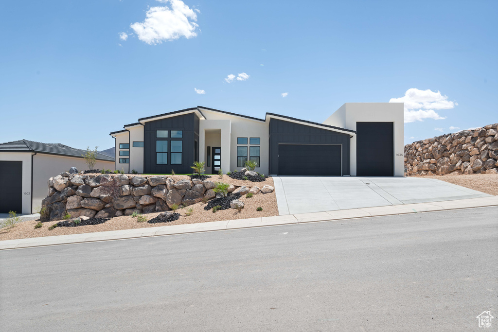 Contemporary house featuring a garage, driveway, and stucco siding