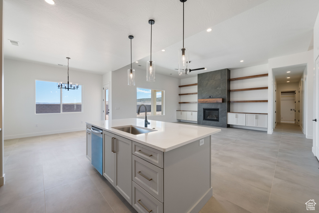 Kitchen with a sink, a chandelier, stainless steel dishwasher, a tiled fireplace, and plenty of natural light