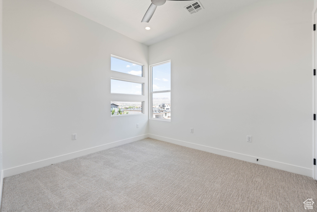 Spare room with light carpet, a ceiling fan, and baseboards