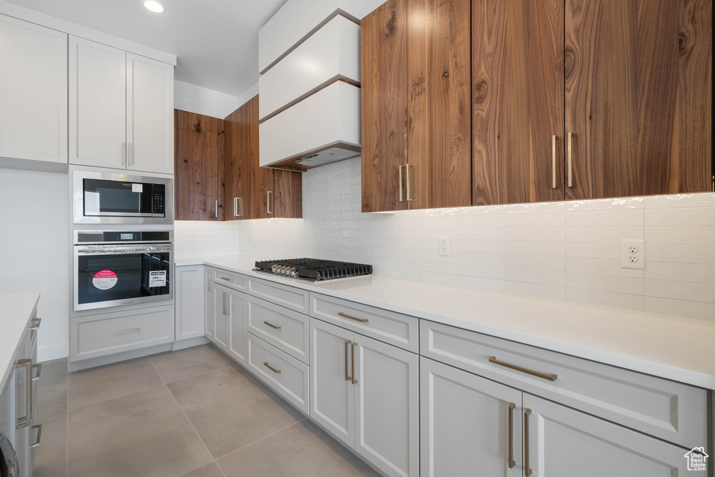 Kitchen featuring appliances with stainless steel finishes, decorative backsplash, light countertops, and light tile patterned flooring