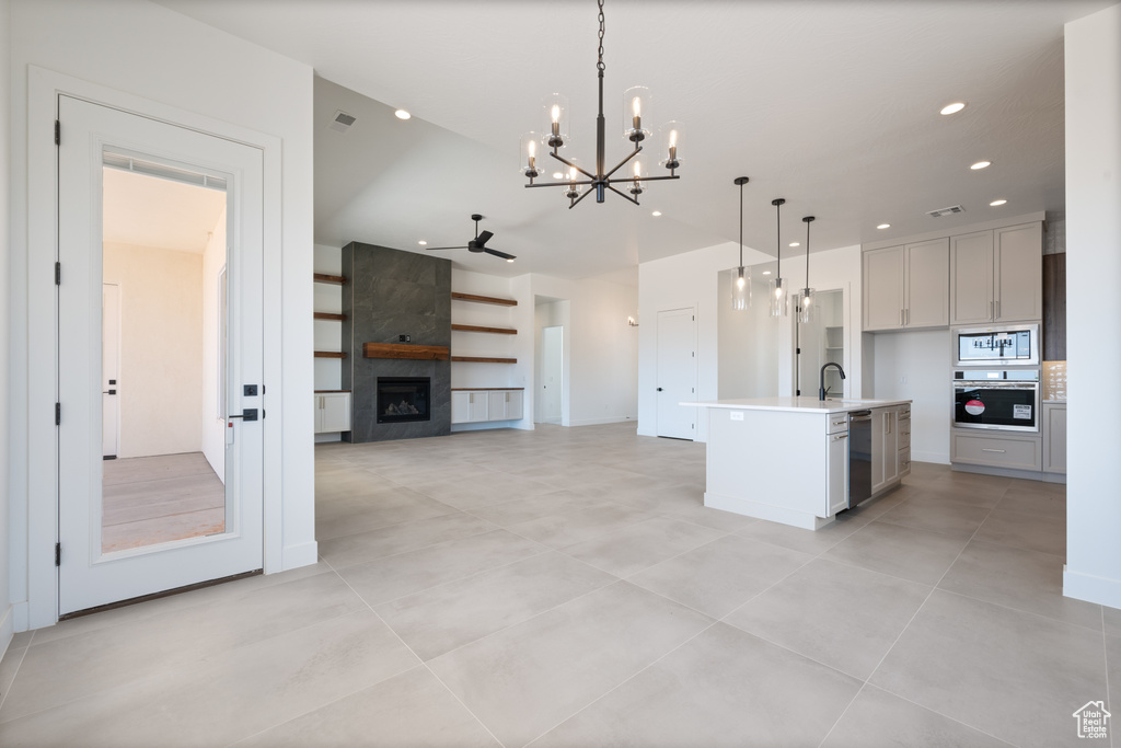 Kitchen featuring appliances with stainless steel finishes, a chandelier, decorative light fixtures, a sink, and a fireplace