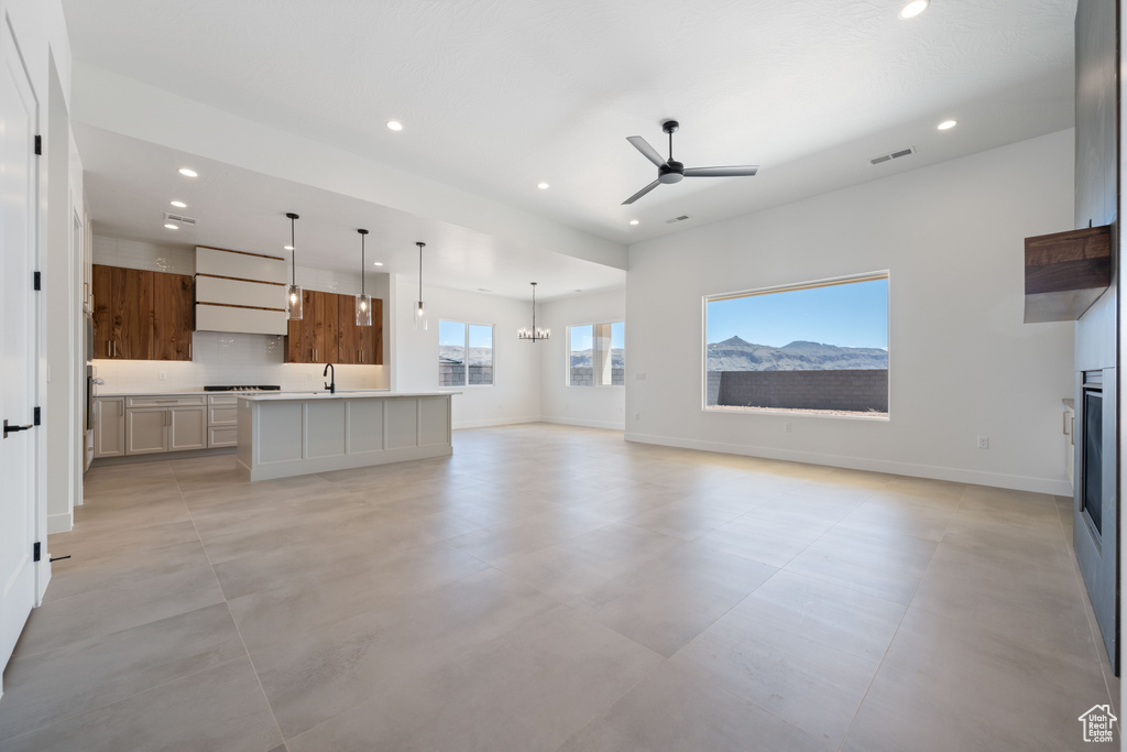 Unfurnished living room with recessed lighting, ceiling fan, baseboards, a chandelier, and a glass covered fireplace