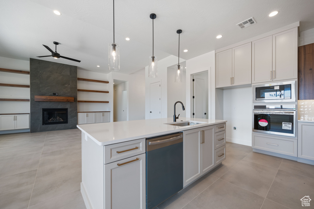 Kitchen featuring a sink, stainless steel appliances, a ceiling fan, light countertops, and a kitchen island with sink