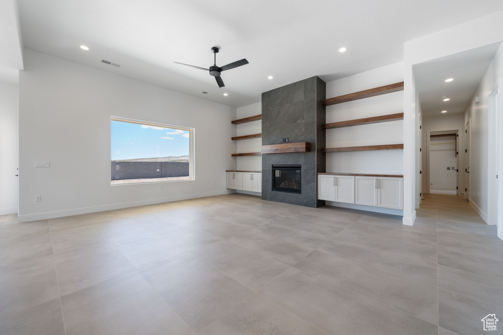 Unfurnished living room with a ceiling fan, recessed lighting, a tile fireplace, and baseboards