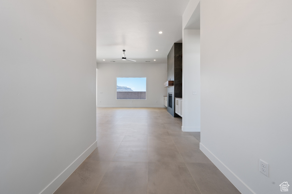 Hall featuring baseboards, concrete floors, and recessed lighting