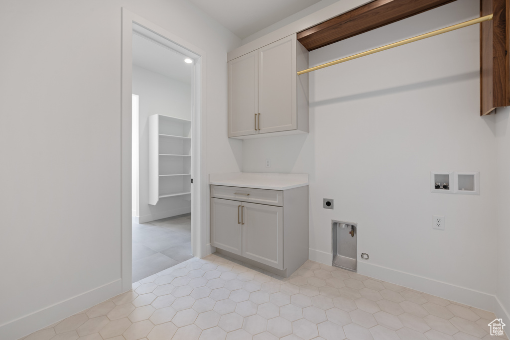 Clothes washing area with electric dryer hookup, hookup for a washing machine, cabinet space, and baseboards