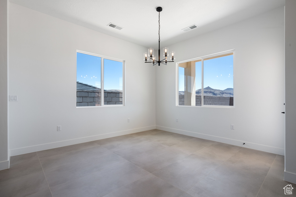 Unfurnished room with a chandelier, baseboards, and concrete floors