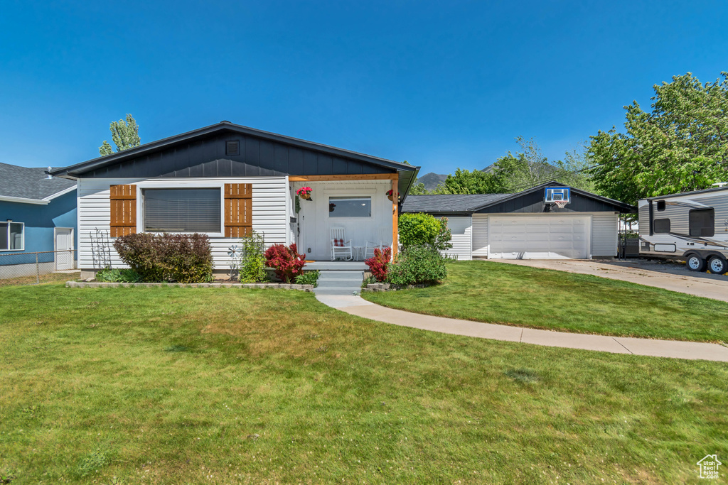 Ranch-style home featuring a garage, concrete driveway, an outbuilding, a porch, and board and batten siding