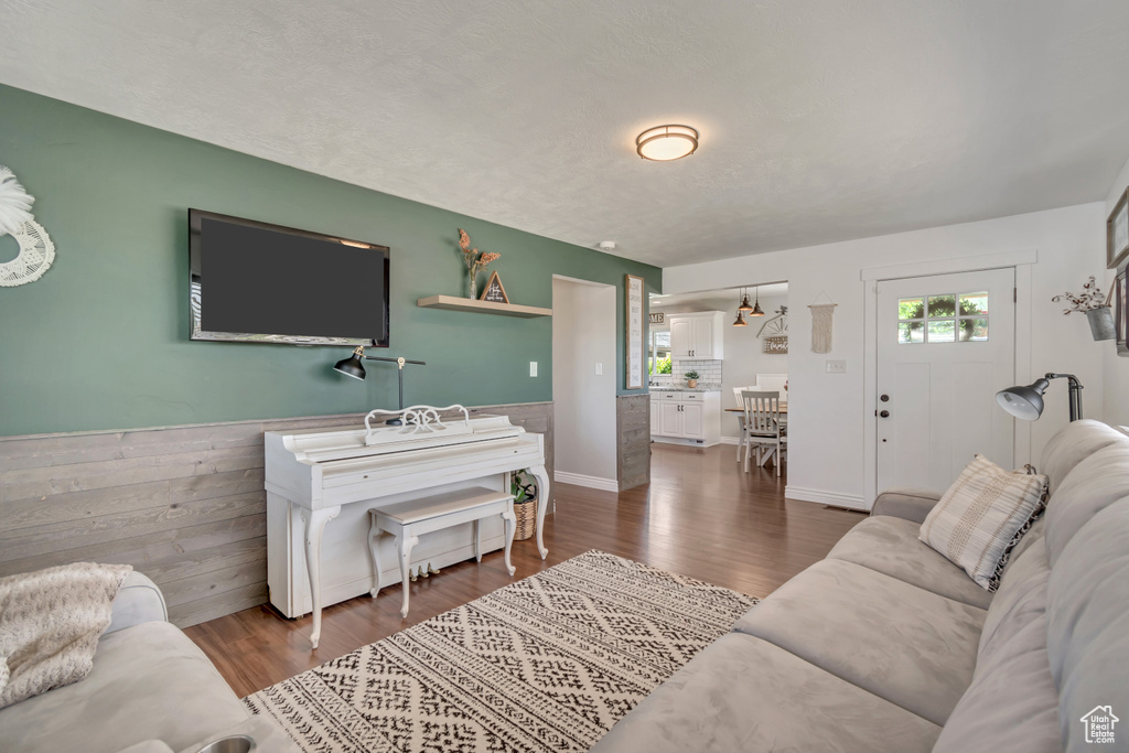 Living area with healthy amount of natural light, wainscoting, and dark wood-style floors