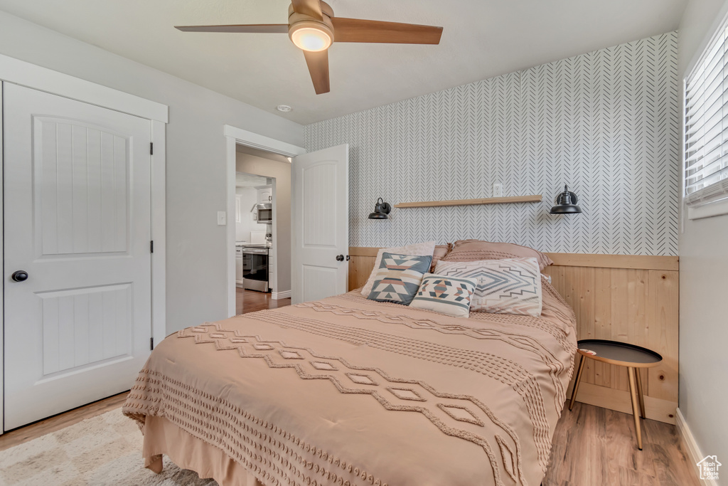 Bedroom featuring wallpapered walls, light wood-style flooring, ceiling fan, and baseboards