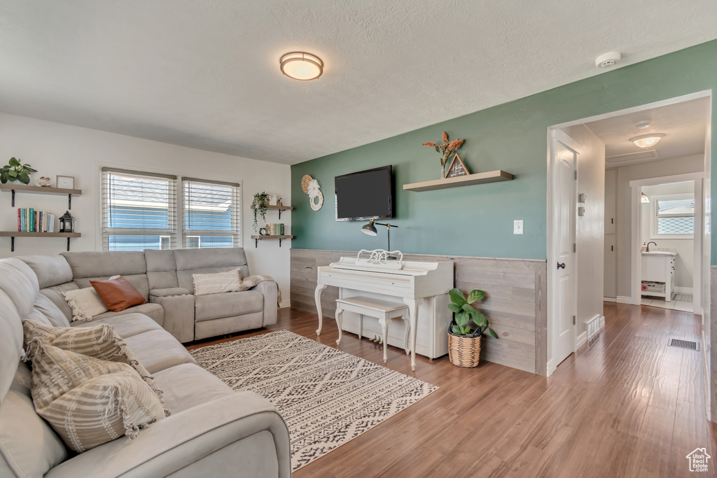 Living room with wood finished floors, wainscoting, and a textured ceiling