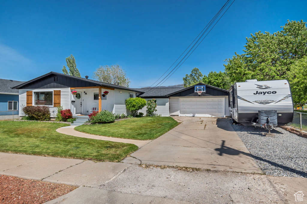 View of front of house featuring an outbuilding, a front lawn, covered porch, and concrete driveway
