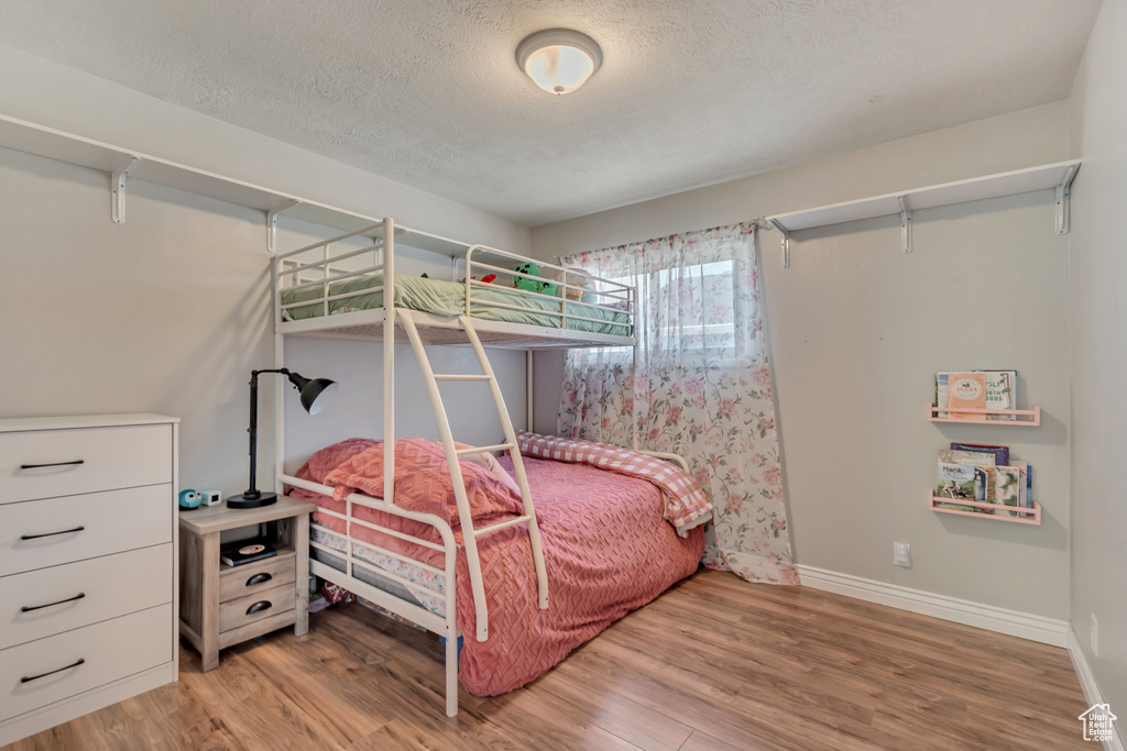 Bedroom featuring light wood-style floors, a textured ceiling, and baseboards