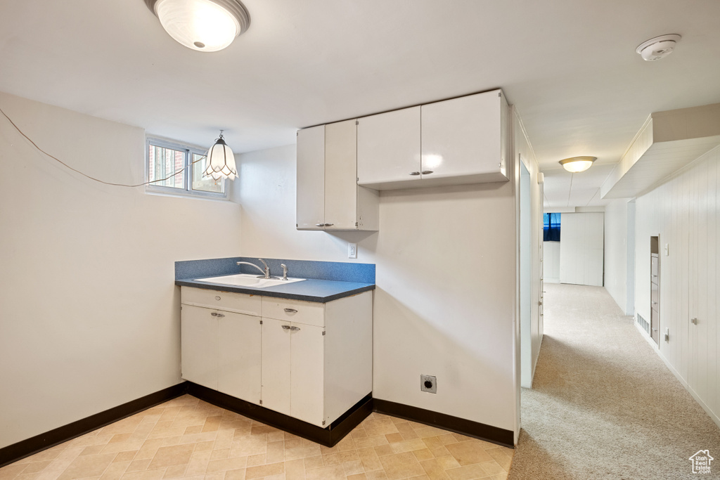 Kitchen featuring a sink, dark countertops, white cabinetry, and baseboards